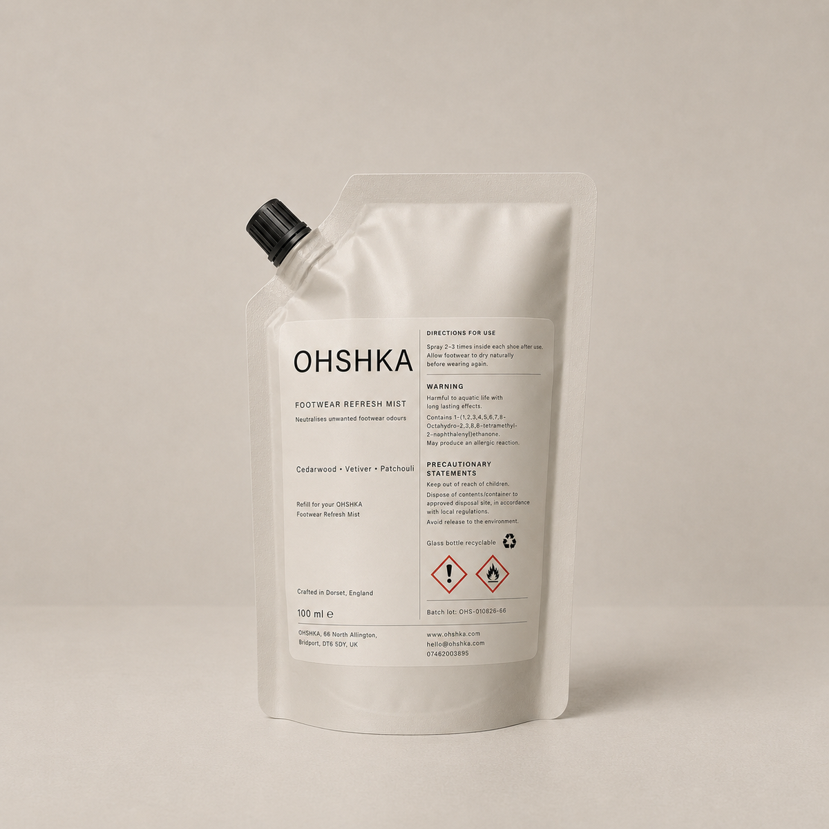 A white refill pouch of OHSHKA Footwear Refresh Mist with a black spout cap, photographed on a neutral light beige background.